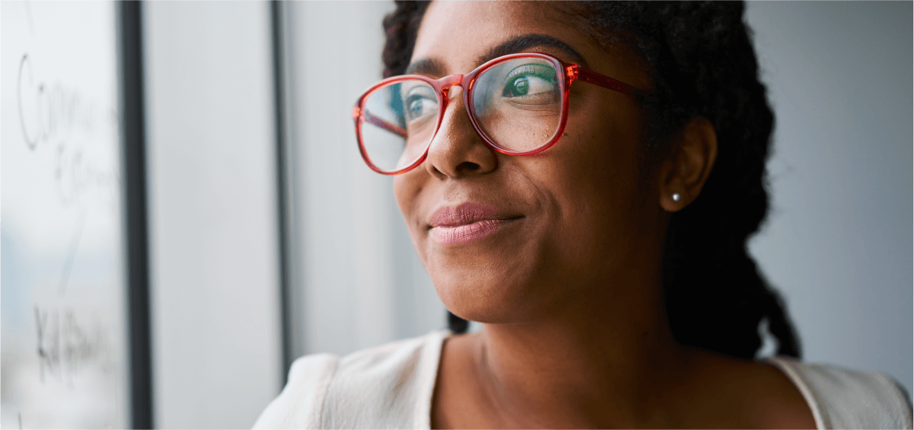 Rear view of a person with red glasses facing a blurred whiteboard