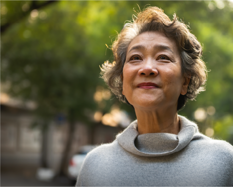 Person from behind with a grey sweater, outdoors with trees in the background