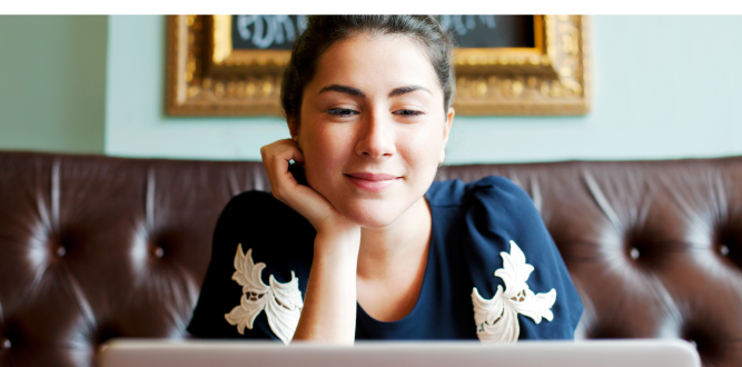 Woman sitting on leather sofa gazing at a screen.