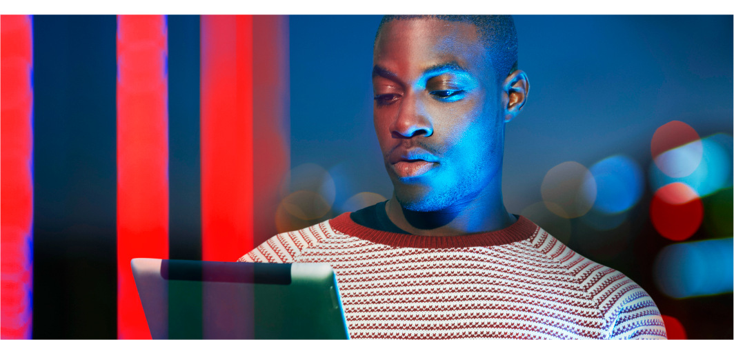 Man working on a tablet device with 3 red vertical lights in the background