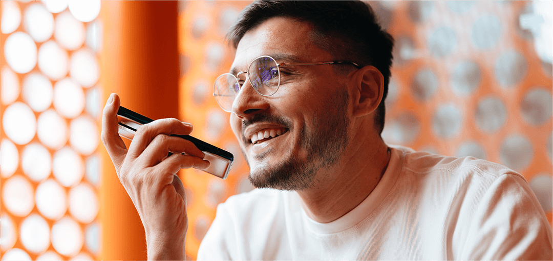 A person holding a smartphone to their ear, sitting in front of an orange and white patterned background