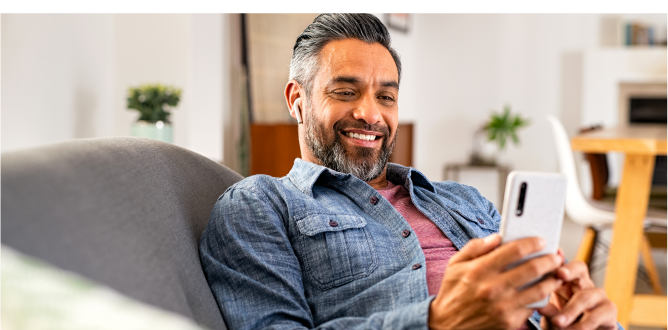 Happy man reclining on sofa swiping through phone.